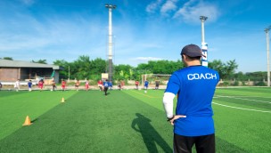 Coach overlooking the pitch with athletes on it.