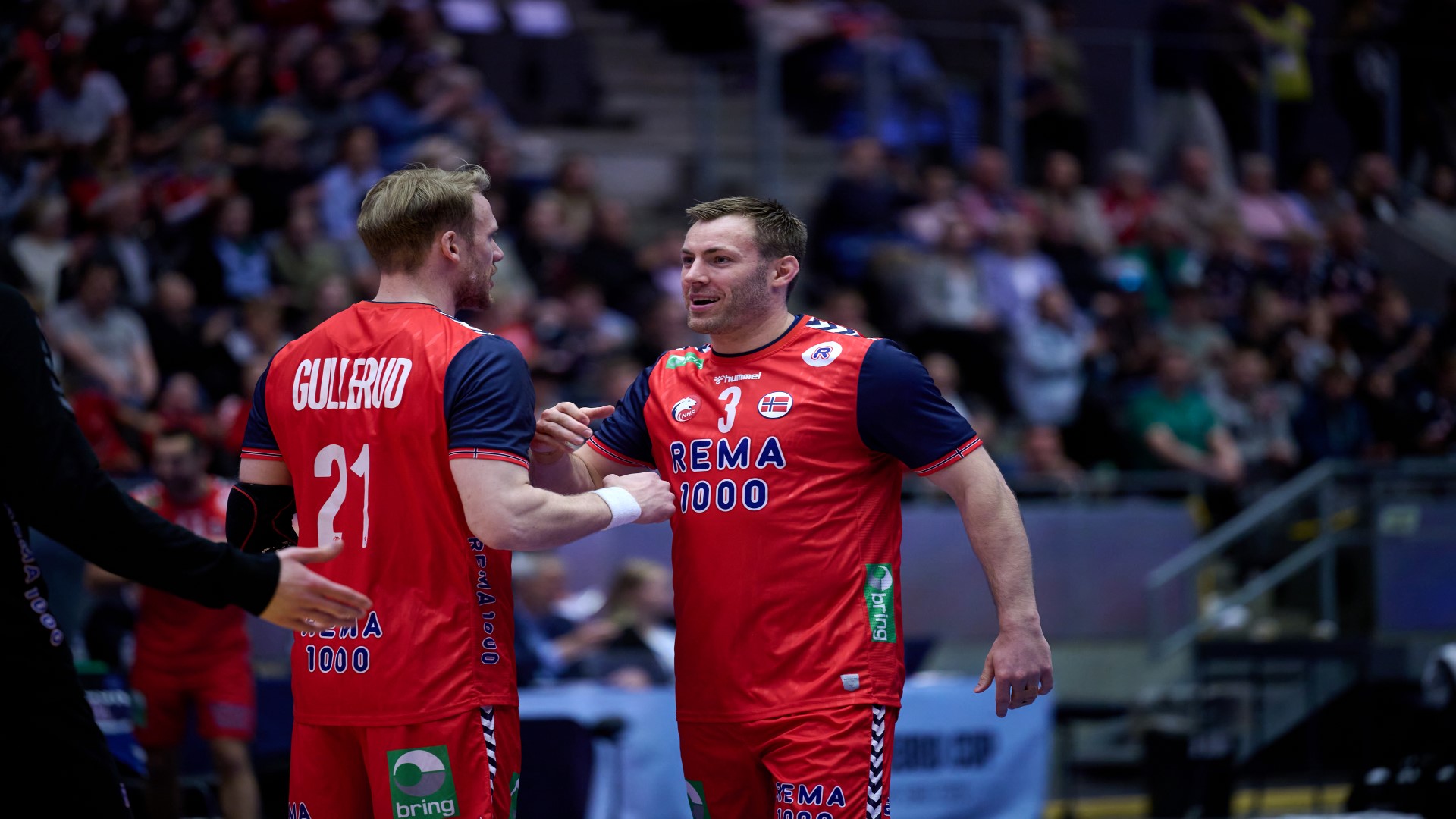 Two handballplayers from the Norwegian mens team in a game on the court, standing face to face.