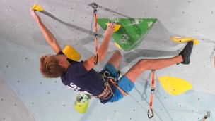 Young athlete in the climbing wall inside, almost hanging upside down