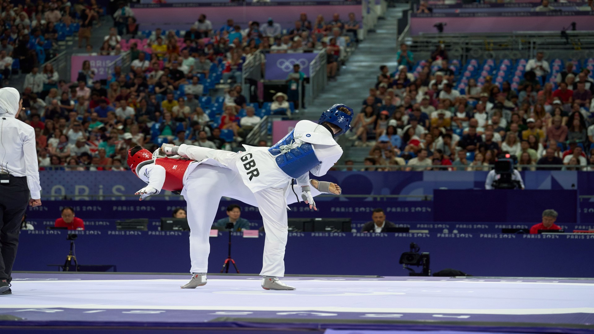Two athletes during an Olympic competition, both kicking each other with a straight leg.